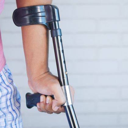 A man uses a crutch to hold himself up