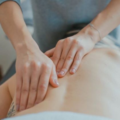 A physiotherapist places their hands along the back of a patient