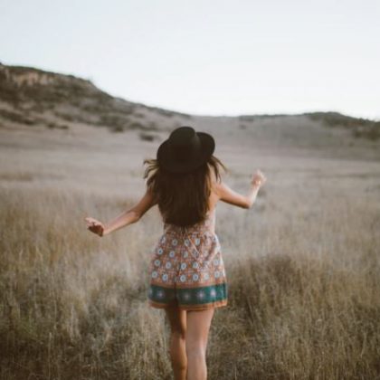 A woman frolics around a grassy hill