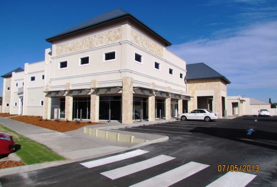 The exterior of the Eversmile Dental building has cream-coloured pillars, a black roof, a car park directly outside of the front entrance, and a pedestrian crossing that leads to the pathway