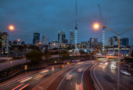 The Perth city skyline at night time, with a view of the freeway in the foreground