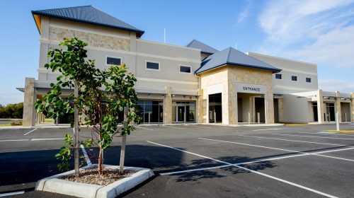 Brecken Health Front Entrance and car park. The building has a grey roof and yellow/ white walls
