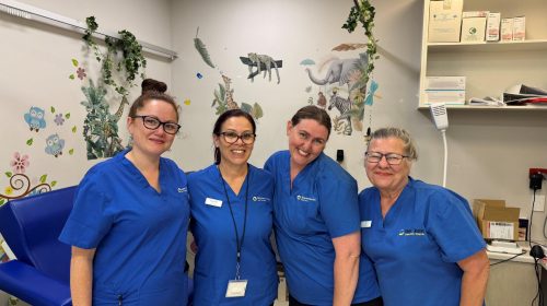 Four Brecken Bunbury nurses smile at the camera in a consulting room that is decorated with vines and animal stickers