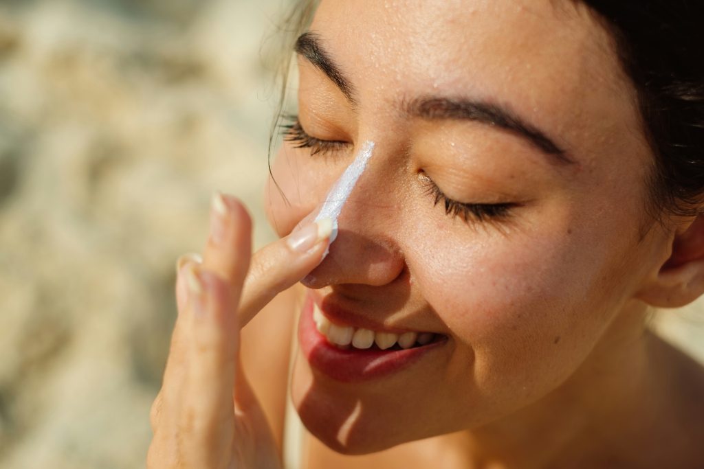 staying sunsmart - woman putting on sunscreen on her nose