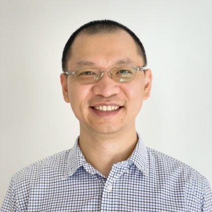 Dr Chenhui Shi smiles at the camera. He is wearing a blue and white shirt and glasses.
